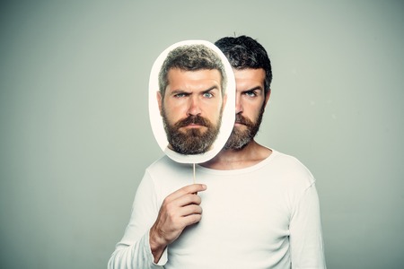 Barber fashion and beauty. Guy or bearded man on grey background. Man with long beard and mustache. Feeling and emotions. Hipster with sad face hold portrait nameplate.の写真素材