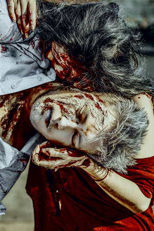 Halloween vampire girl biting man victim. Woman and war soldier with wounds and red blood outdoors. Zombie couple on sunny day.の写真素材