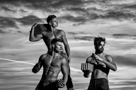 men or bodybuilders, handsome, young, male athlete people with sexy, muscular torso outdoors in sunset sky. guys holds present boxes for valentines or christmas holidays, black and whiteの写真素材