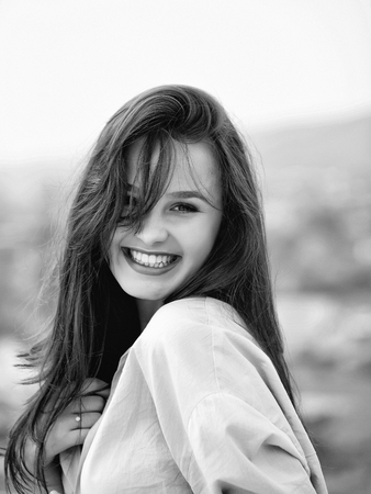 Young pretty woman or girl with cute sexy happy smiling face and long brunette hair in pink shirt posing outdoor on blurred backgroundの写真素材