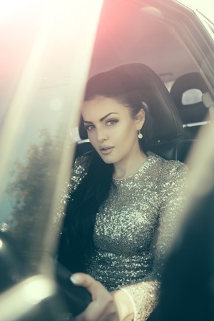 Girl driving car. Woman in party dress with golden sequins in auto. Summer vacation and travelling concept. Holidays, birthday, anniversary celebration. Fashion and style.の写真素材