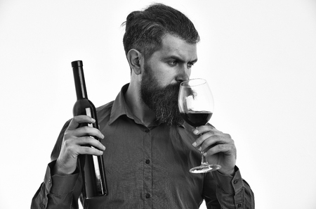 bearded man, long beard, brutal caucasian hipster with moustache holding wine bottle and glass with alcoholic drink, has serious face, in brown shirt isolated on white background, copy spaceの写真素材