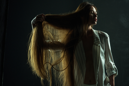 Girl has no makeup and healthy hair on black background. Woman with stylish long hair in underwear. Haircare and shampoo. Beauty salon and fashion. Hairdresser and barber.の写真素材
