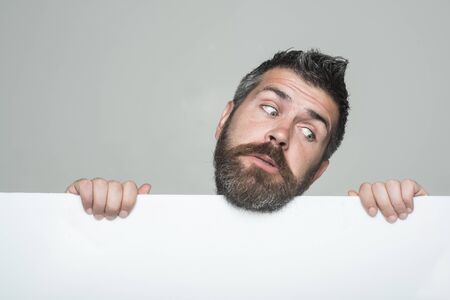 Hipster with sad face hold paper. Man with long beard and mustache. Feeling and emotions. Guy or bearded man on grey background. Barber fashion and beauty marketing.の写真素材