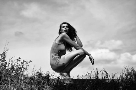 Pretty girl young woman model with slim sexy body in green undershirt sits on summer day on sky backgroundの写真素材