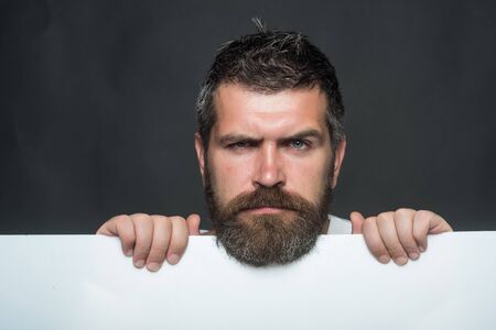 Guy or bearded man on black background. Hipster with sad face hold paper. Man with long beard and...