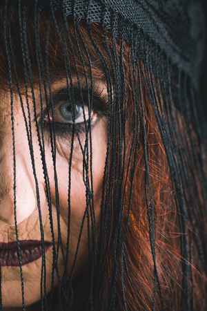 Halloween traditional party. holiday celebration. Halloween old lady. old woman in black veil. woman with red hair and makeup.の写真素材
