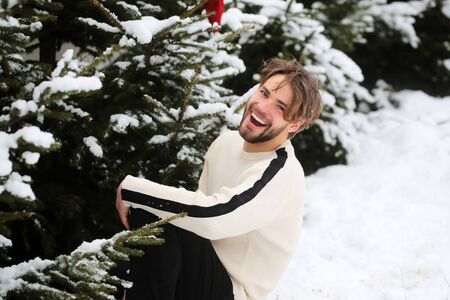 Happy man enjoying winter day on nature. Macho smiling on snow in fir wood. Christmas and new year. Holidays celebration conceptの写真素材
