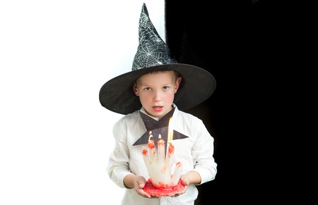 Halloween Party and traditional costume. Kid with bloody candle. Holiday and celebration. Small boy in spider web witch hat. Halloween child with serious face on black and white background.の写真素材