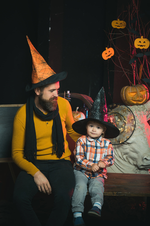 Halloween party and celebration. Boy kid with happy face and bearded man at pumpkin. man and child in witch hat. Halloween Holiday and celebration. Father and small son, fathers day.の写真素材