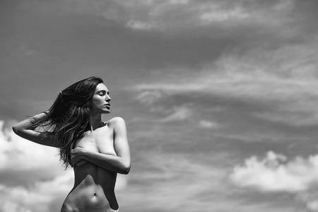 Pretty girl young woman or girl model with slim sexy body and long brunette hair with bare chest or breast poses summer day on blue sky, copy spaceの写真素材