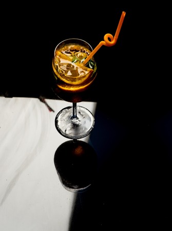 Fruit slice and cocktail glass at bar. lcoholic beverage and lemon staurant. Party and summer vacation. Cocktail on black round. Drink and food.の写真素材