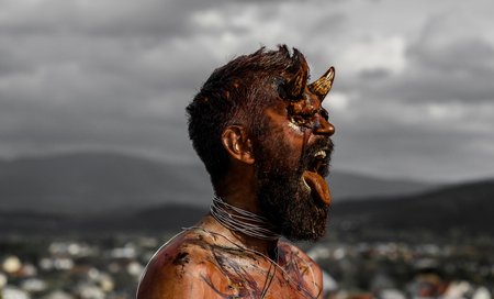 Halloween hell, evil, horror, darkness concept. Demon man with beard showing tongue. Vampire or dragon with open mouth. Satan with red blood and wounds on face. Devil head with bloody horns.の写真素材