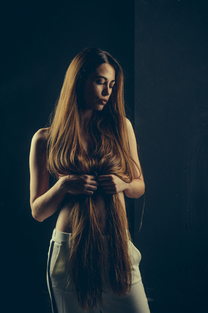 Hairdresser and barber. Haircare and shampoo. Girl has no makeup and healthy hair on black background. Beauty salon and fashion. Woman with stylish long hair and naked chest.の写真素材