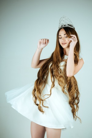 Hairdresser and cosmetics. Beauty salon and wedding fashion. Girl has fashionable makeup and healthy hair on grey background. Haircare and prom queen. Woman with long hair white dress and crown.の写真素材