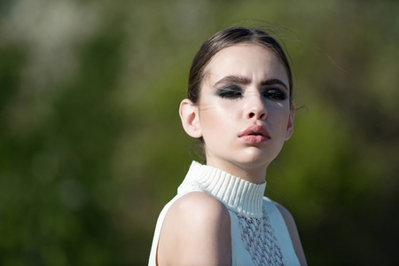 Woman or girl wear golden earrings with makeup on face on blurred natural environment. Fashion, beauty, visage concept, copy spaceの写真素材