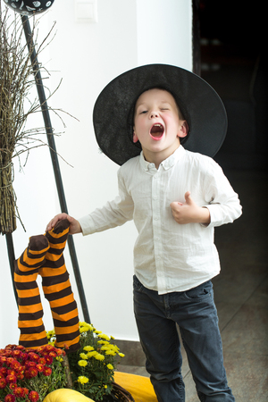 Halloween Small boy in spider web hat at striped socks. Party and traditional food. Halloween child with happy face. Kid with orange pumpkin in witch hat. Holiday and celebration.の写真素材