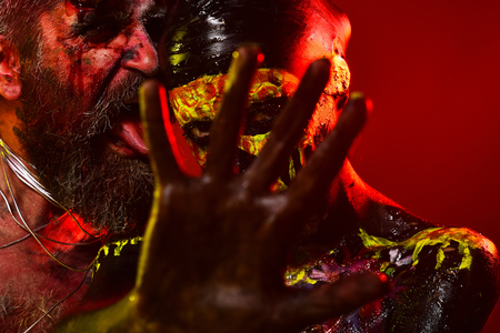 Halloween couple with stop hand gesture on red background. Man with bloody beard lick woman skull makeup. Prohibition, denial, rejection concept.の写真素材