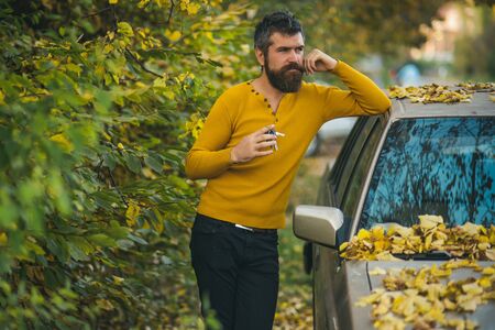 travelling and fall holiday. Man with beard at car. man in autumn forest. Autumn guy outdoor....