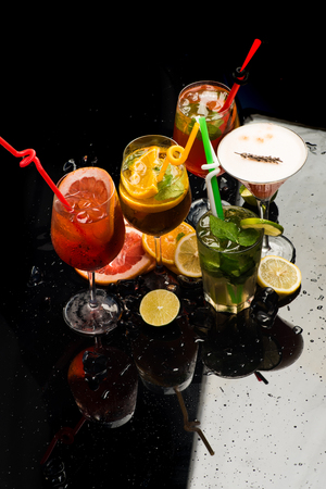 cocktail glass with colorful drink and drinking straw with fruit slices on black backgroundの写真素材