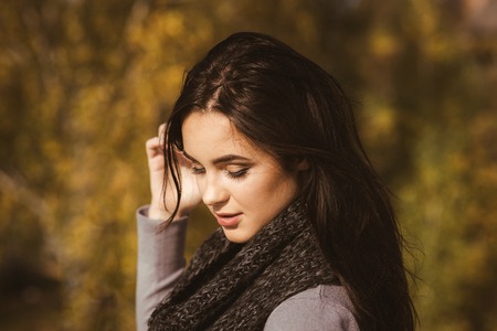 Girl with makeup face on autumn landscape. Woman with long brunette hair hairstyle on sunny day on nature. Beauty, fashion, youth, health concept.の写真素材