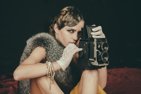 Woman with retro hair, makeup and old camera. Pin up pretty fashion model photographer. Girl with vintage photo camera. beauty, retro look, pinup fashion. media and new technology, journalism.の写真素材