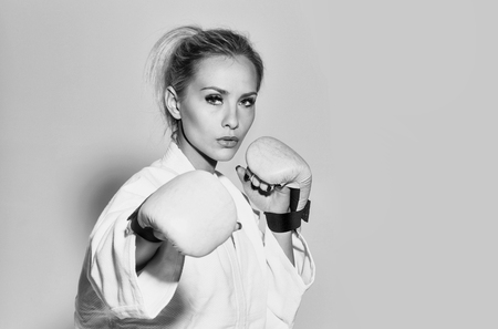 Pretty girl or sexy woman, boxer, fighter, athlete wearing boxing gloves and sexi white shirt with blond, hair on grey background, copy space. Extreme sports and struggleの写真素材