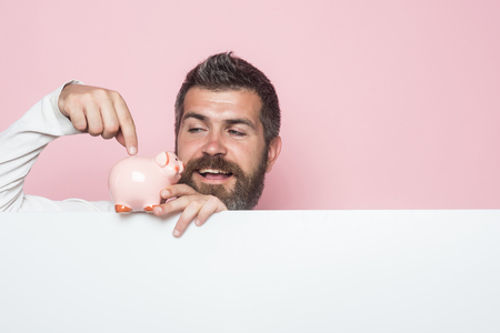 Guy hold moneybox or piggy bank for savings. Sale and black friday shopping. Bankruptcy and handout. Crisis and loan. Man with beard on happy face take credit.の写真素材