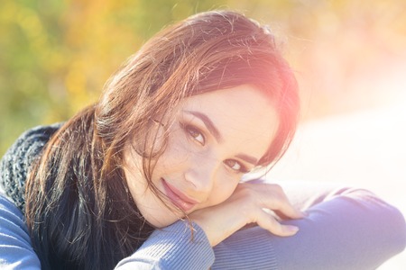 Fashion, beauty concept. Girl with makeup face smiling on sunny day. Skincare, youth, health. Woman with long brunette hair on autumn nature. Energy, joy, serenity.の写真素材
