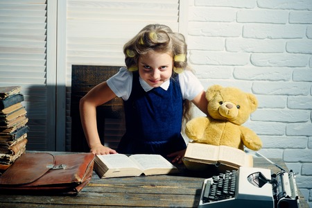 Child with briefcase and typewriter on table. Small girl with curler in hair read book. Little baby...