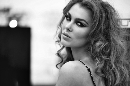 Pretty girl or beautiful woman with stylish makeup and long curly hair wearing pink polka dot dress on blurred backgroundの写真素材