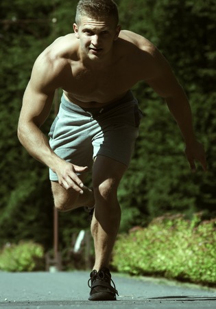 Man runner or jogger with muscular body run on road on sunny summer day. Speed, movement, energy concept.の写真素材