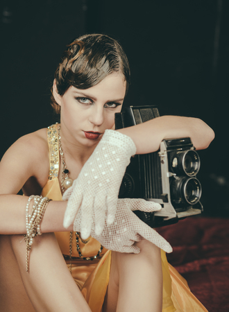 media and new technology, journalism. Pin up pretty fashion model photographer. Woman with retro hair, makeup and old camera. beauty, retro look, pinup fashion. Girl with vintage photo camera.の写真素材