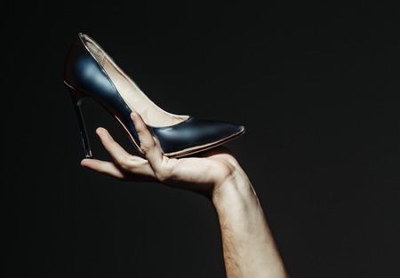 Presenting product, promotion, advertising. Shoe on high heel, stiletto, in hand on grey background. Fashion, vogue, style. Black friday, cyber, online shopping, sale, ecommerce.の写真素材