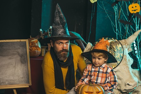 Halloween Father and small son, fathers day. man and child in witch hat. Boy kid with happy face and bearded man at pumpkin. Halloween Holiday and celebration. party and celebration.の写真素材