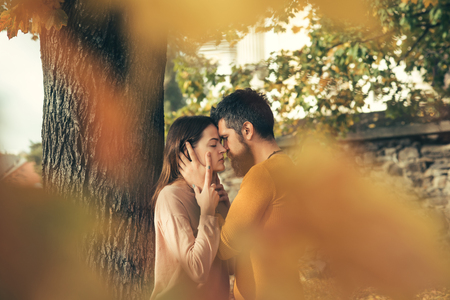 Love relationship and romance. Man and woman at yellow tree leaves. Autumn happy couple of girl and man outdoor. Nature season and fall holiday. Couple in love in autumn park.の写真素材