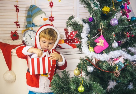 New year small boy at decoration toy. Santa claus kid decorating Christmas tree.. Xmas party celebration. Winter holiday and vacation. Christmas happy child with gift box, boxing day.の写真素材