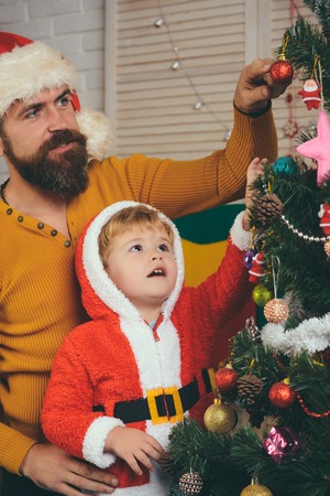 New year small boy son and man with toy. Winter holiday and vacation. Christmas happy child and father. Santa claus kid and bearded man at Christmas tree. Xmas party celebration, fathers day.の写真素材