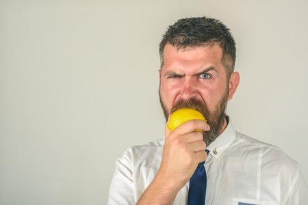 Fruit and healthy organic food. Vitamin citrus at hipster on white background. Vegetarian, health and wellbeing. Dieting and fitness. Man with long beard eat lemon, copy spaceの写真素材