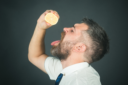 Fruit and healthy organic food. Vitamin citrus at hipster on black background. Man with long beard squeeze lemon. Vegetarian, health and wellbeing. Dieting and fitness.の写真素材