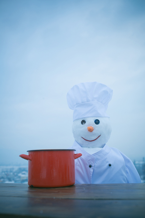 Xmas or christmas cooking. Snowman chef in winter with kitchen pot. Happy holiday celebration. New year snowman in cook hat. Christmas food cooking.の写真素材
