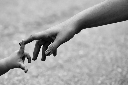 Little fragile baby hand touching mothers finger on gray backgroundの写真素材