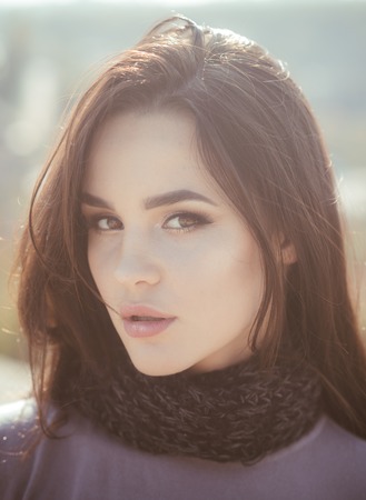 Girl with long brunette hair on nature. Woman face with makeup on sunny day. Cosmetics, visage, make up. Skincare, youth, health. Fashion, beauty concept.の写真素材