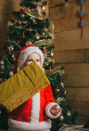 Xmas party celebration. Winter holiday and vacation. New year small girl, boxing day. Christmas happy child with present box. Santa claus kid at Christmas tree.の写真素材