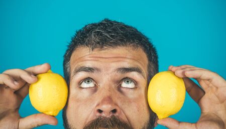 Vitamin citrus at hipster on blue background. Fruit and healthy organic food. Dieting and fitness. Vegetarian, health and wellbeing. Man with long beard hold lemon.の写真素材