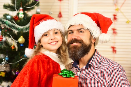 Xmas party celebration, fathers day. Winter holiday and boxing day. Christmas happy child and father with present box. New year small girl, man with gift. Santa kid, bearded man at Christmas tree.の写真素材