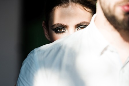 Woman look out behind man shoulder. Couple of fashion models. Cosmetics, beauty, visage concept. Man with beard in shirt. Girl with makeup face.の写真素材