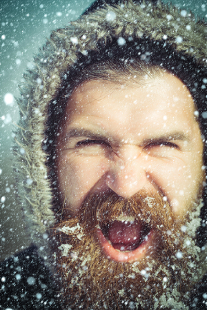 snow christmas new year concept Winter holiday and vacation. Xmas party celebration. New year guy on blue sky with snow. Christmas man with long beard. Hipster in coat and hood.の写真素材