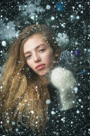 christmas new year snow concept christmas girl in winter mitten hold cell phone in fur cover at xmas tree, new year holiday and party celebration, new technology and buy online, cyber monday and smsの写真素材