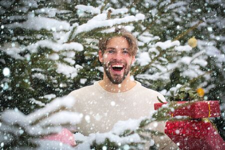 christmas new year snow concept Macho smiling with presents on winter day. Season greetings and xmas...